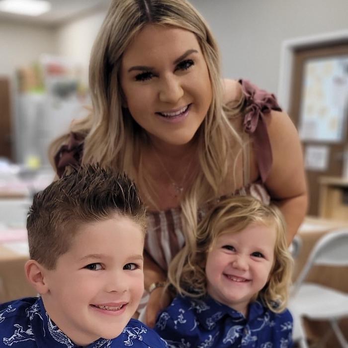 A photo of a teacher with two adorable smiling children