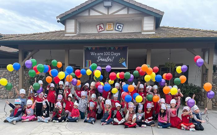 A group of children wearing hats holding balloons in front of ABC Child Care Center