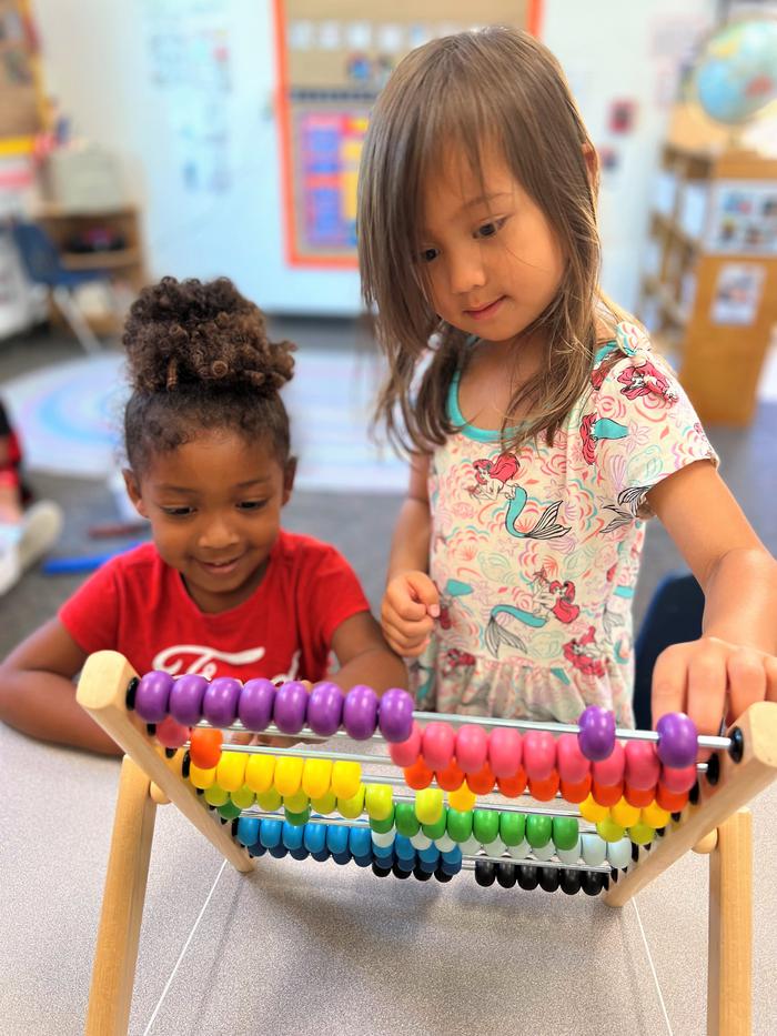 Two children playing with a colorful abacus.