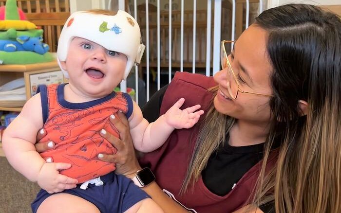 A smiling toddler with a teacher