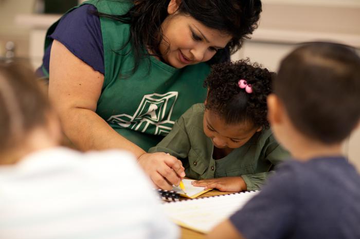 A photo of a teacher with pre kindergarteners